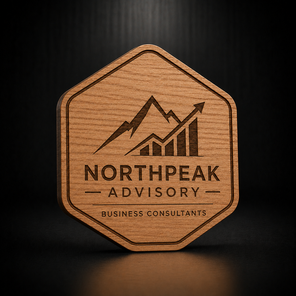A hexagonal wooden plaque or coaster featuring a laser-engraved mountain and bar-chart graphic with the text 'NORTHPEAK ADVISORY' and 'BUSINESS CONSULTANTS' on a dark background.