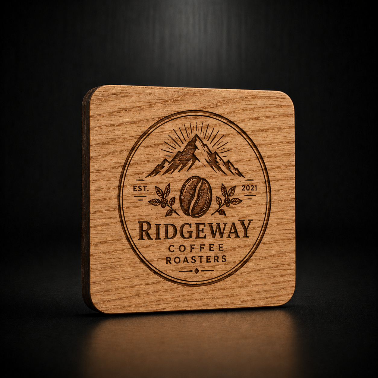 A square wooden coaster with rounded corners, featuring a laser-engraved circular logo for 'Ridgeway Coffee Roasters' with mountains, a coffee bean, and the text 'EST 2021'. The coaster is photographed on a dark, reflective surface against a dark background.